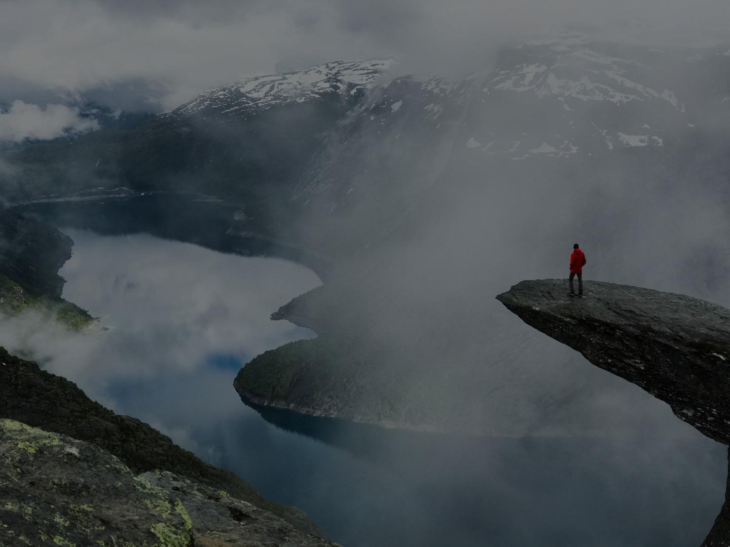 A hiker standing on a cliff edge above a fjord, steady and in control